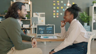 Two colleagues discussing work at a desk.