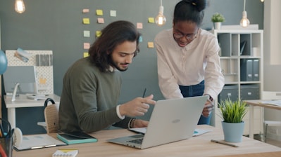 Two colleagues collaborating on a laptop in an office.