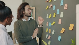 Two colleagues discussing ideas on a sticky note wall.