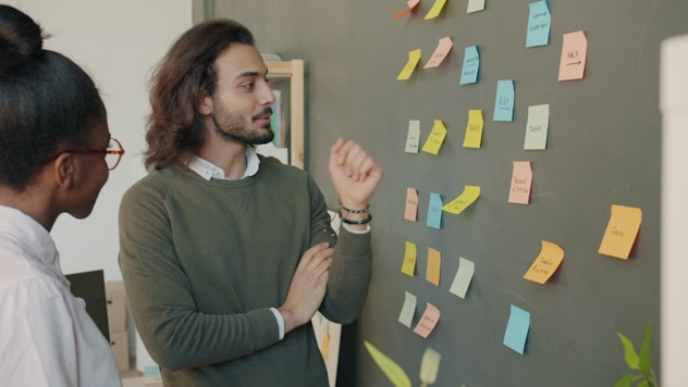 Two colleagues discussing ideas on a sticky note wall.