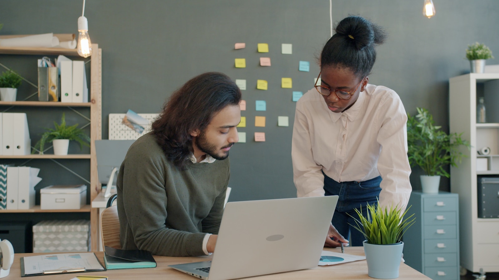 Deux collègues d'une PME B2B revoient leur guide de prospection sur un ordinateur portable au bureau