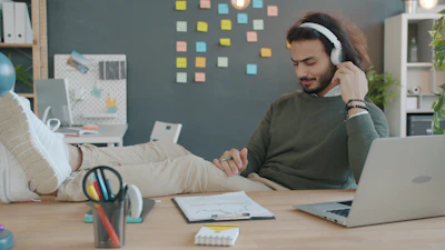 Hombre trabajando con audífonos y libreta en home office,