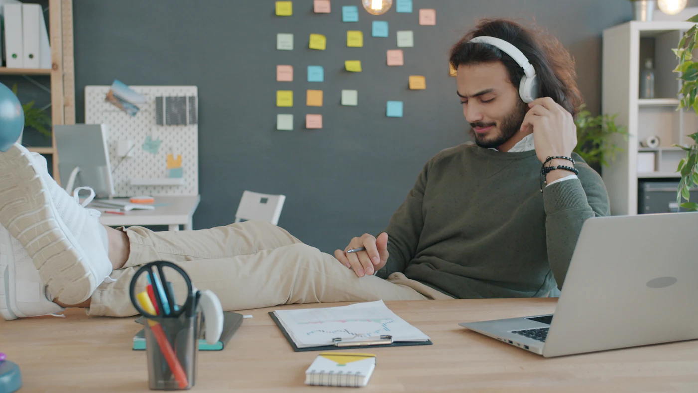Person wearing wireless over-ear headphones working at a home office desk