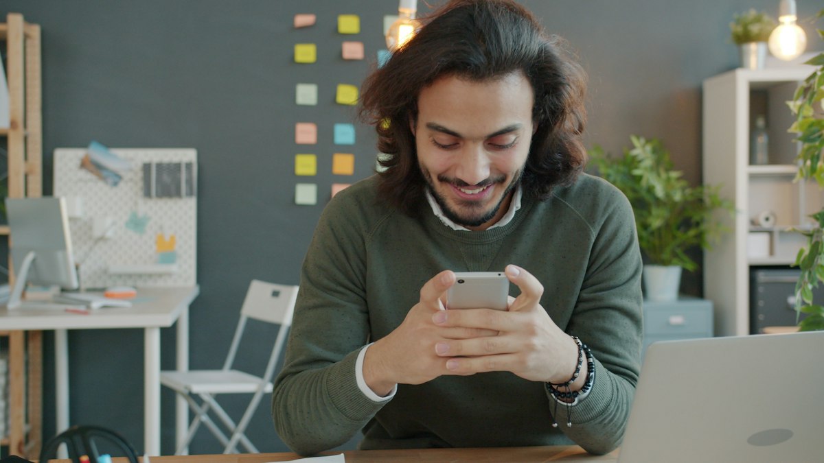 Man smiling while looking at his smartphone