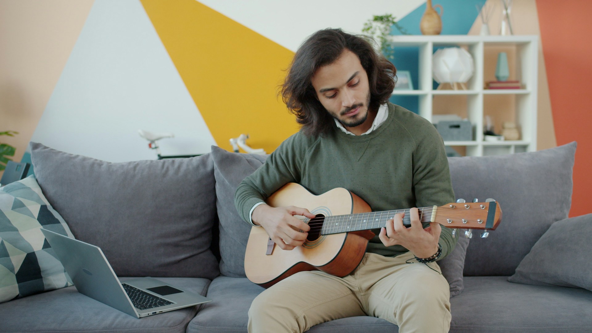 Man playing acoustic guitar on a couch