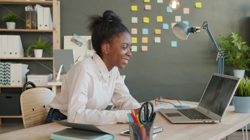Young woman smiling while working on a laptop at desk.