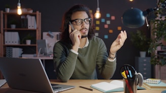 Man talking on phone at desk with laptop.