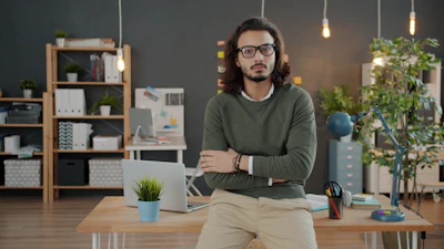 Man with glasses and arms crossed in office.