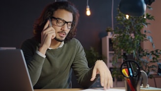 Man talking on phone at desk with laptop
