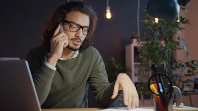 Man talking on phone at desk with laptop