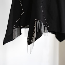 Black fabric with silver studs and fringe details.