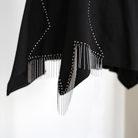 Black fabric with silver studs and fringe details.