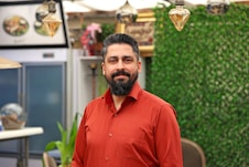 Man with beard in a red shirt smiling indoors