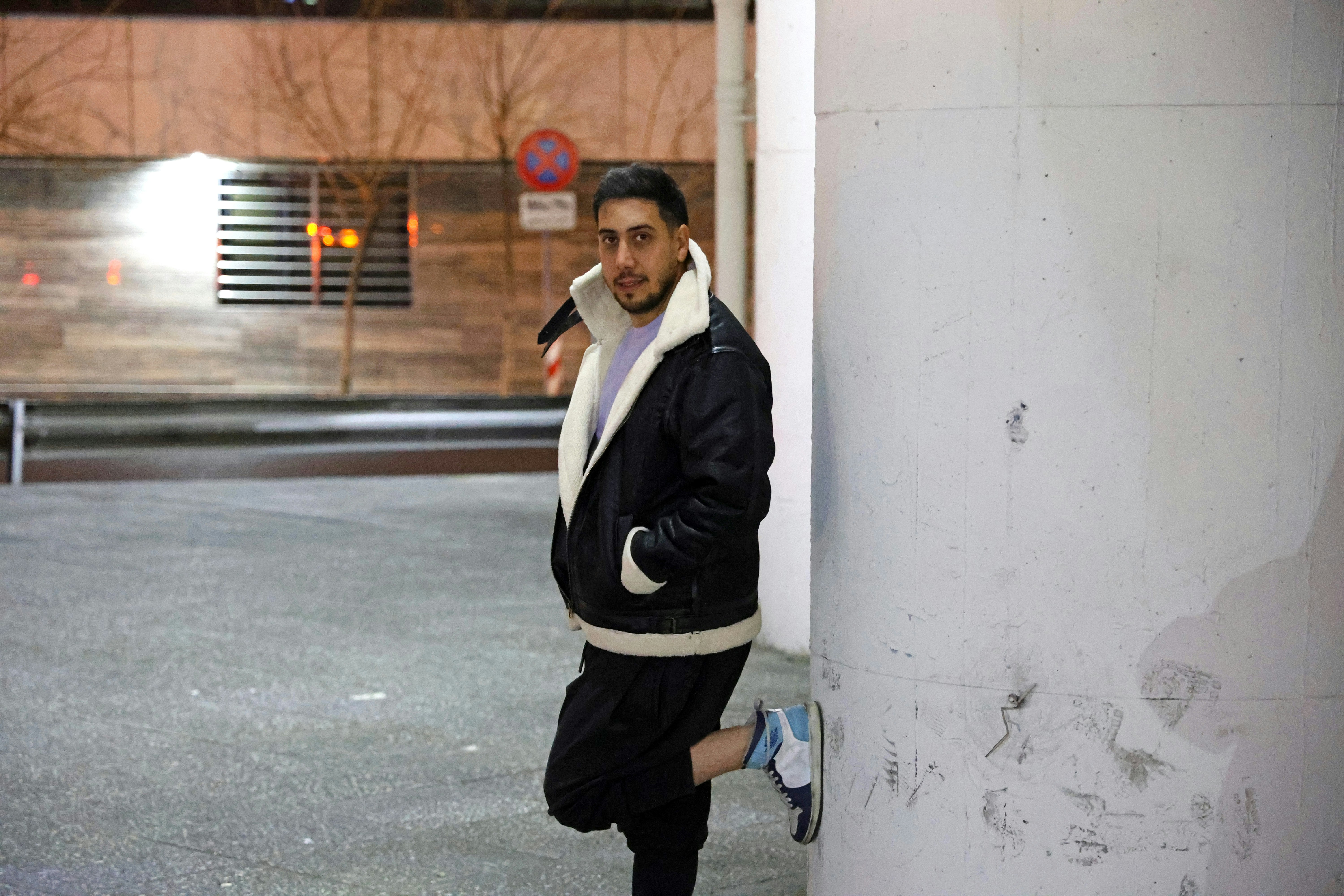 Man leaning against a wall at night.