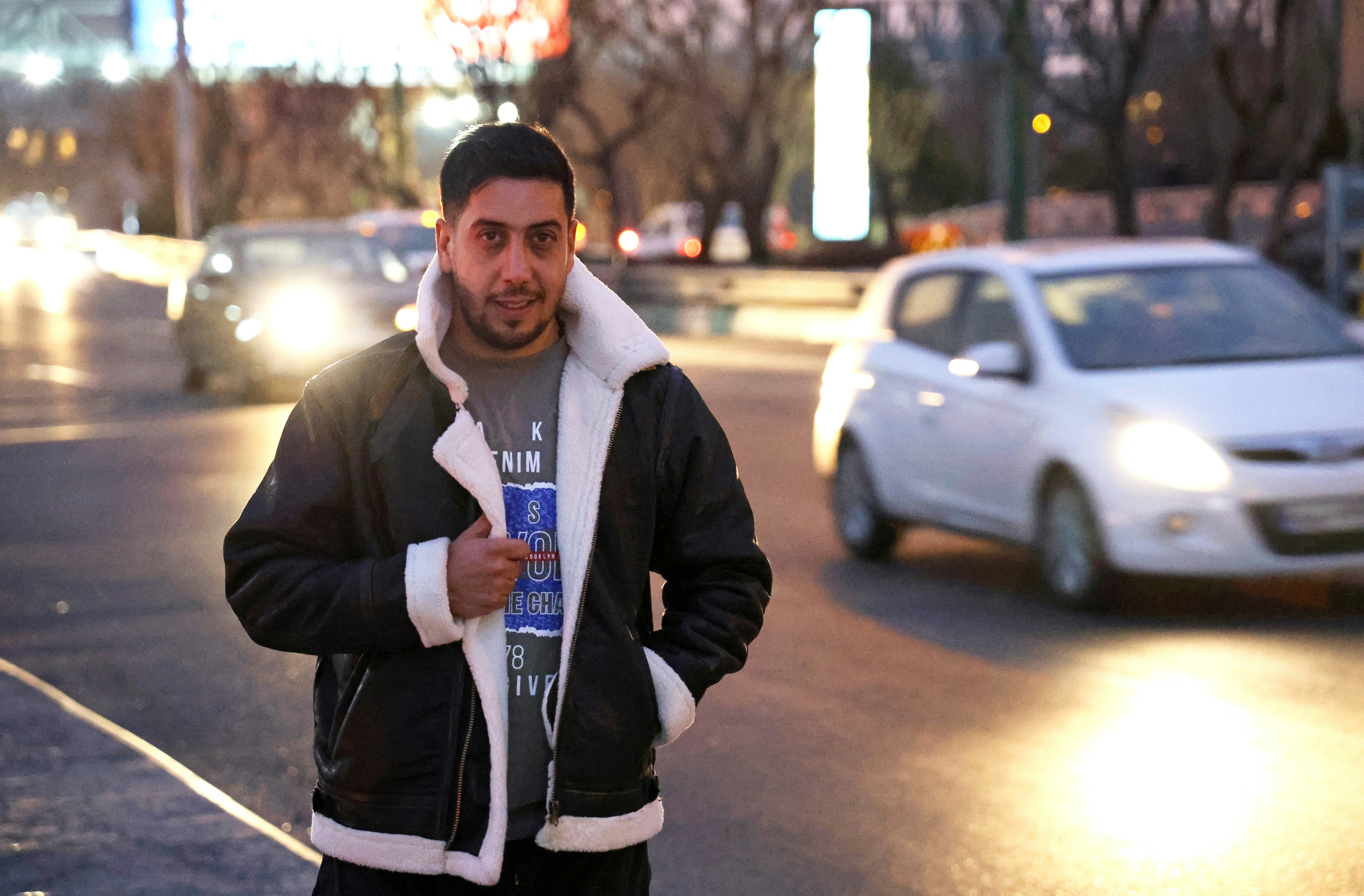 Man standing on street with cars passing