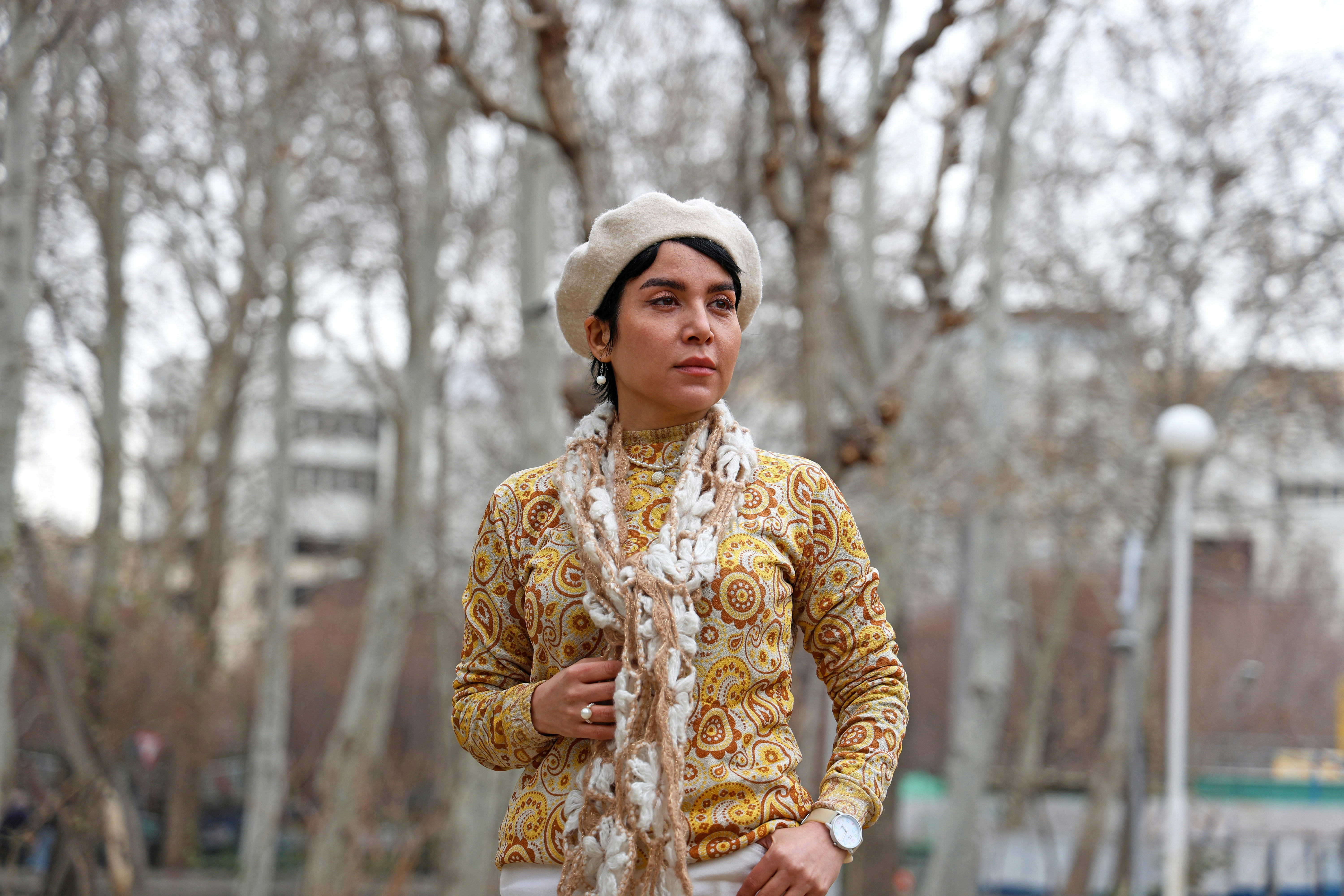 Woman wearing a beret and patterned sweater outdoors.