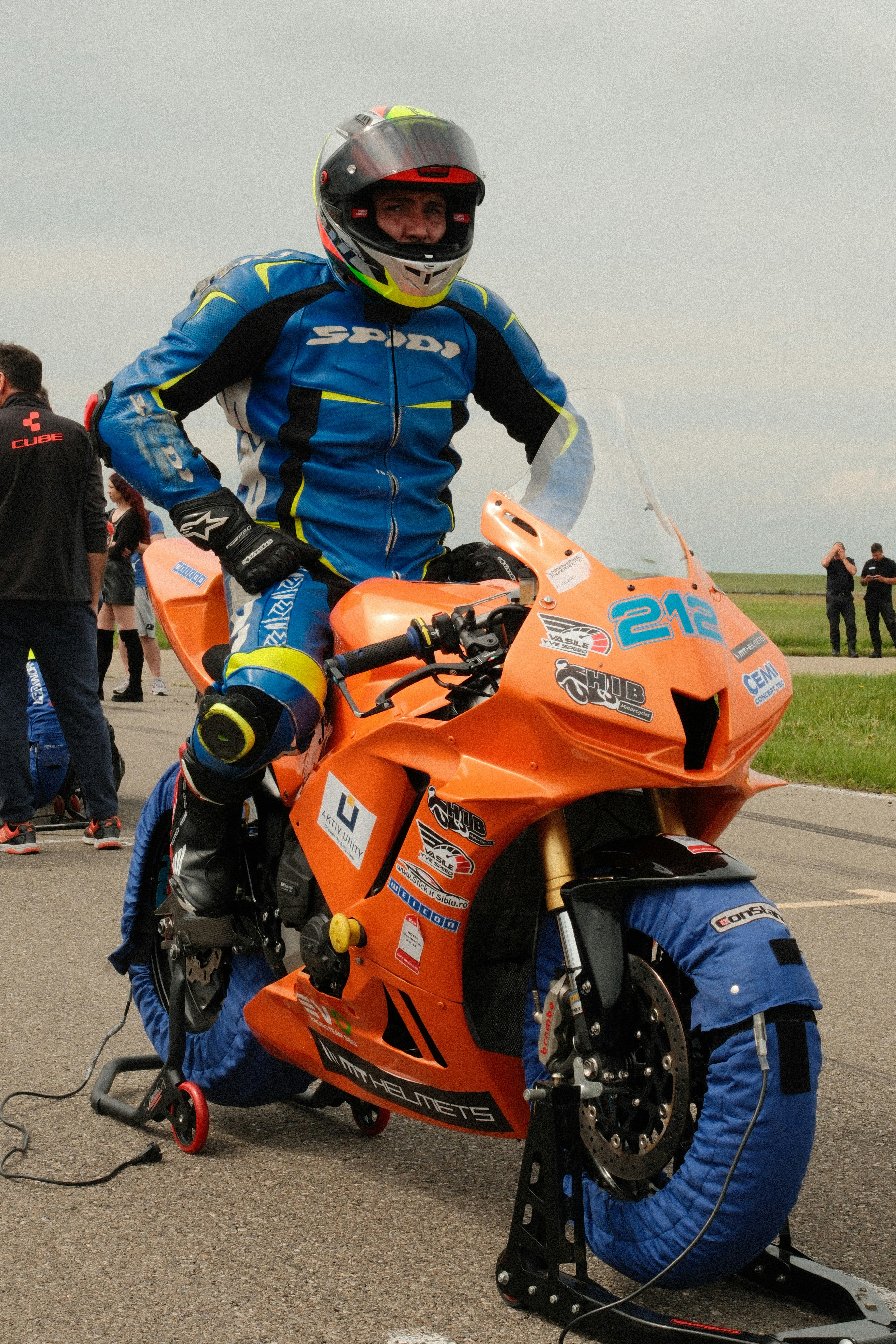 Racer on orange motorcycle with blue tire warmers