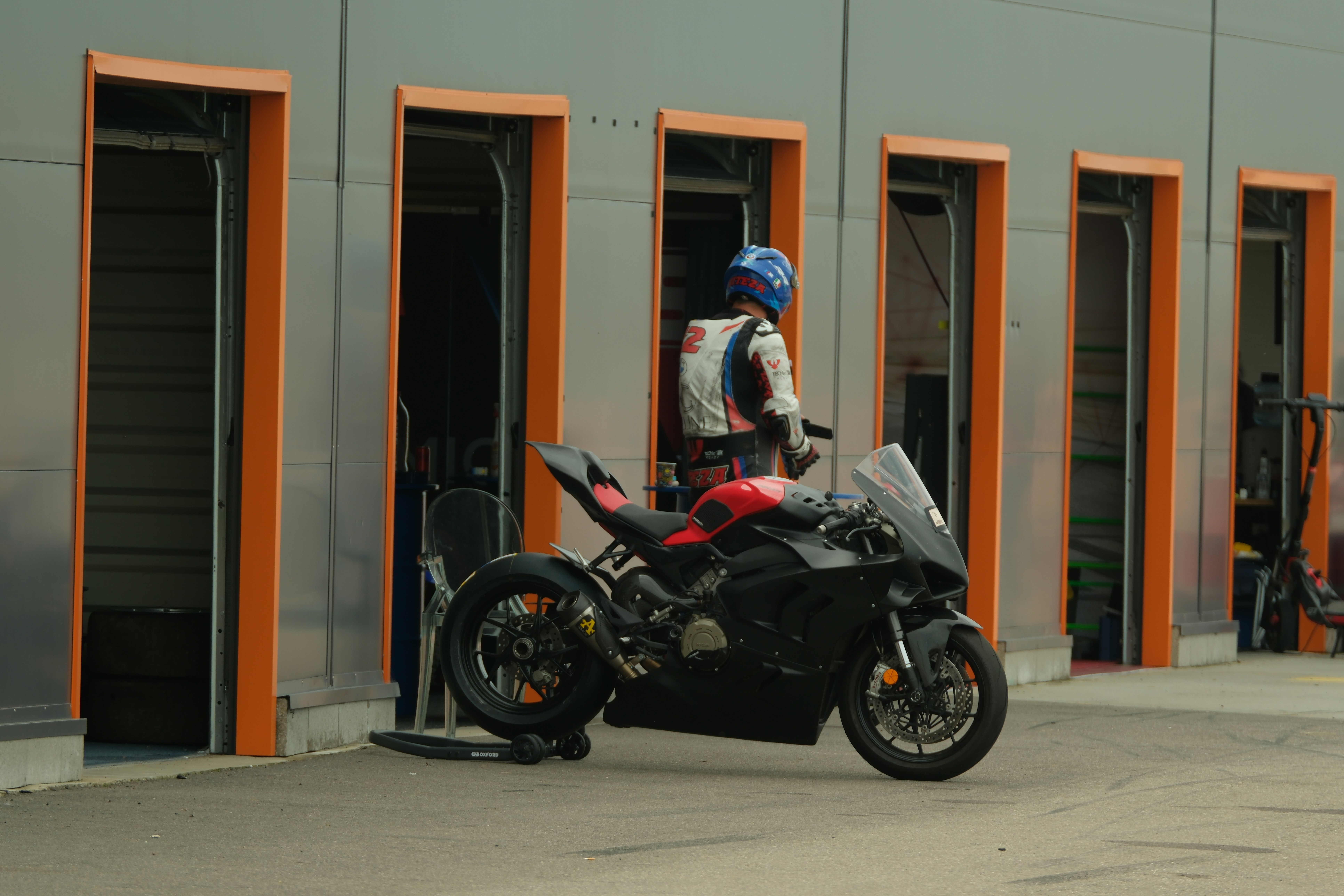 Rider in gear next to a black sport motorcycle.