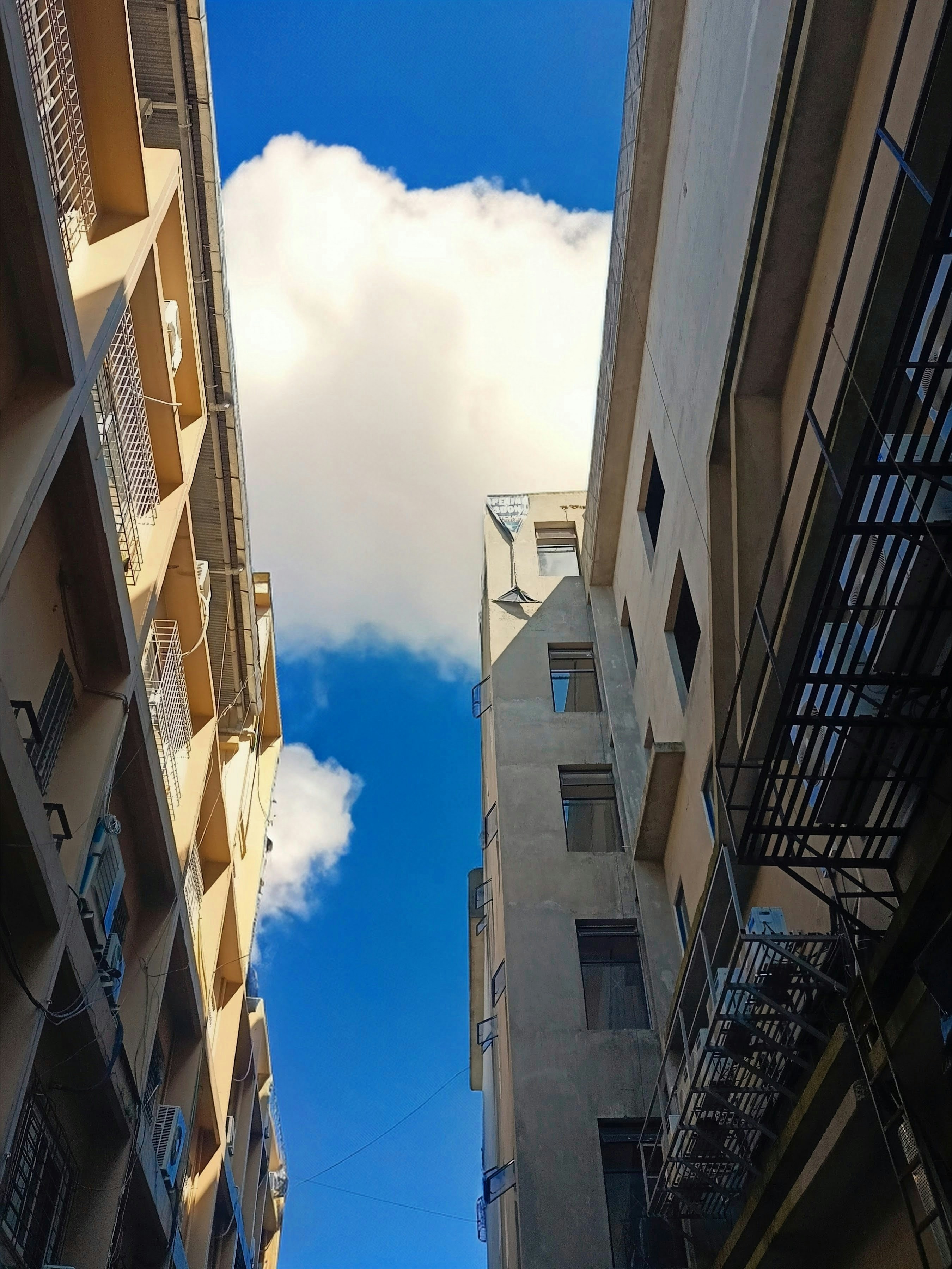 Buildings framing a bright blue sky with clouds
