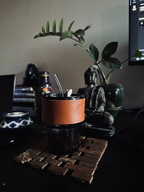 A yerba mate cup with a plant and buddha statue.