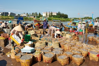 Fishermen unloading baskets of fish at a busy market.
