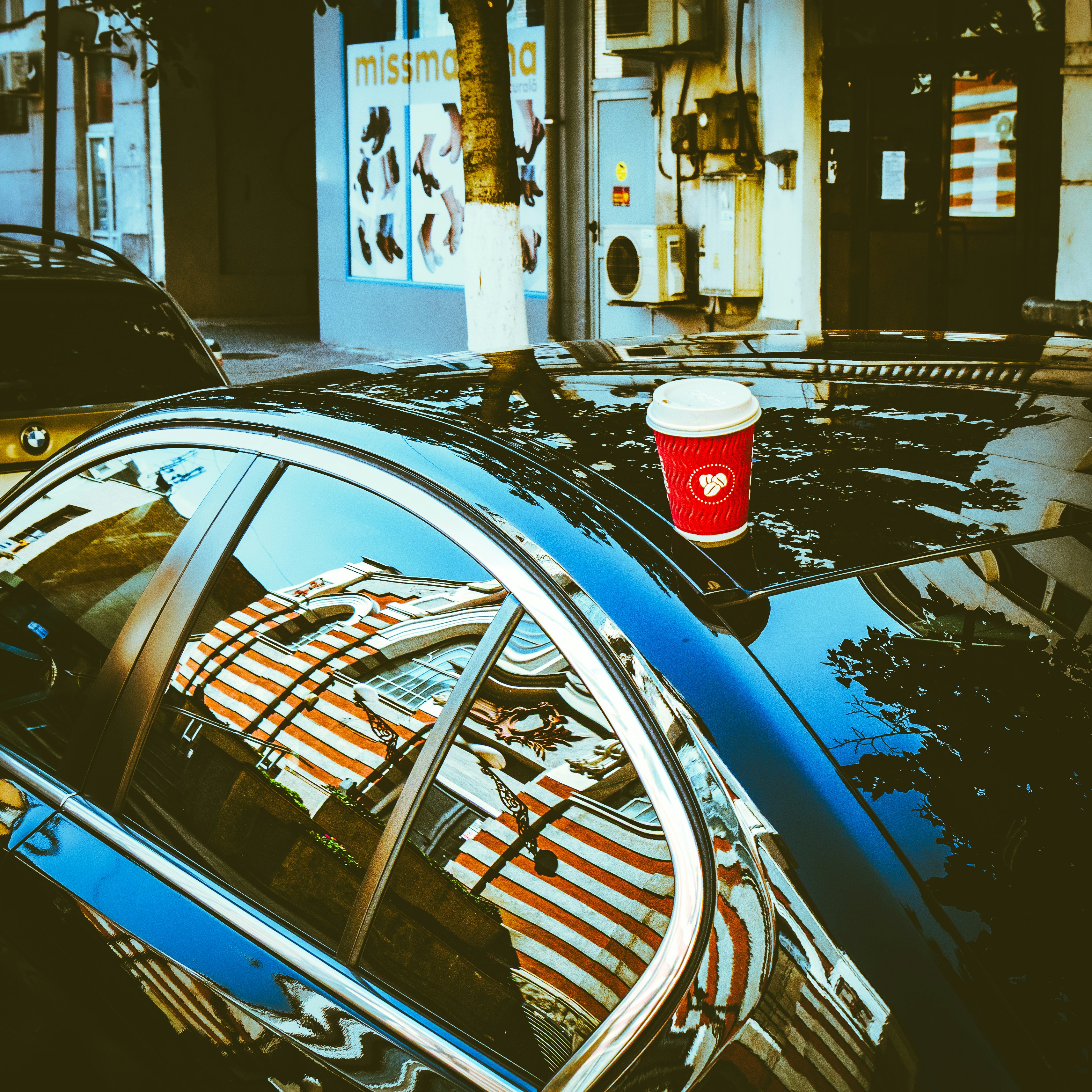 Red coffee cup on car roof with reflection