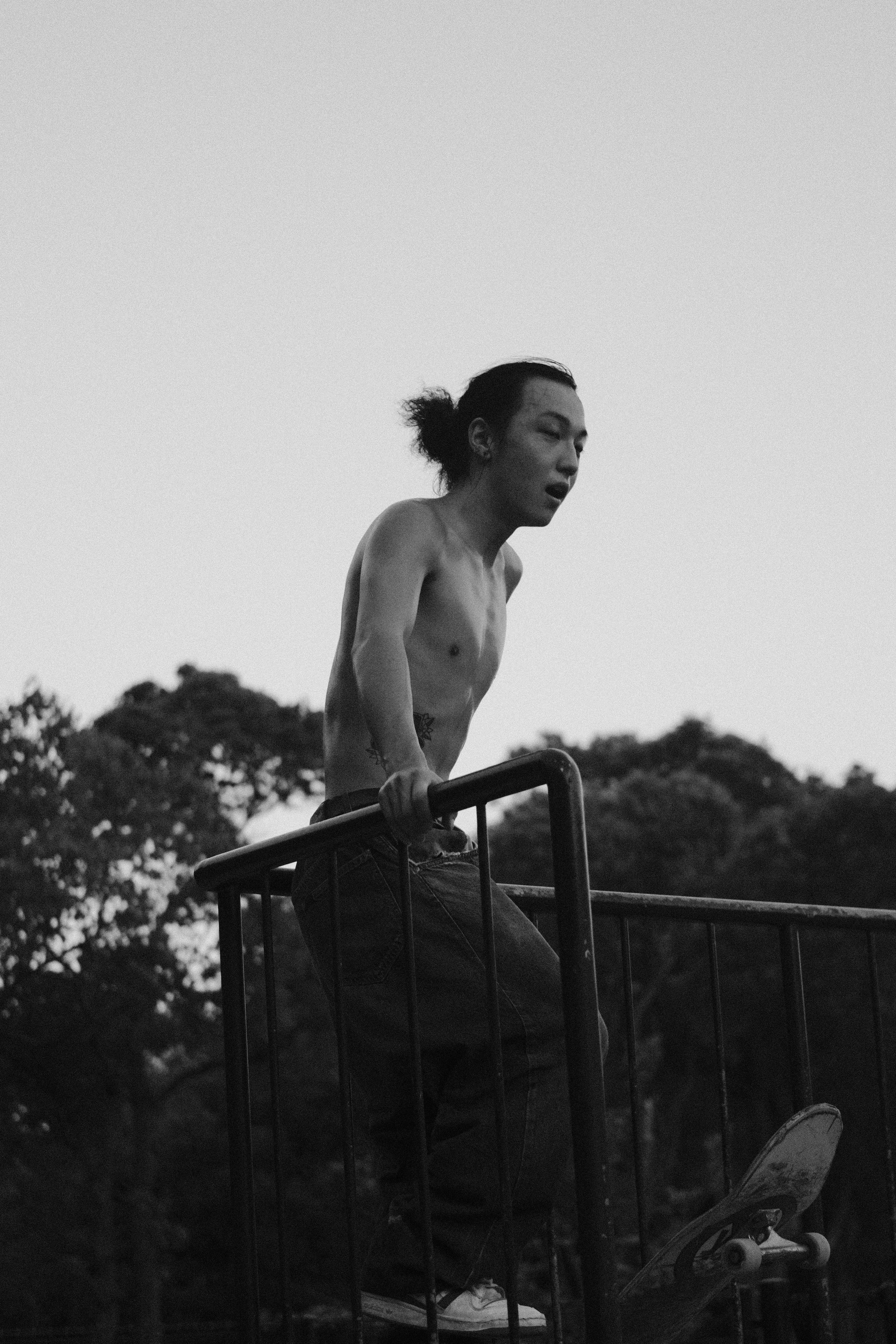 Shirtless man with skateboard at skatepark railing