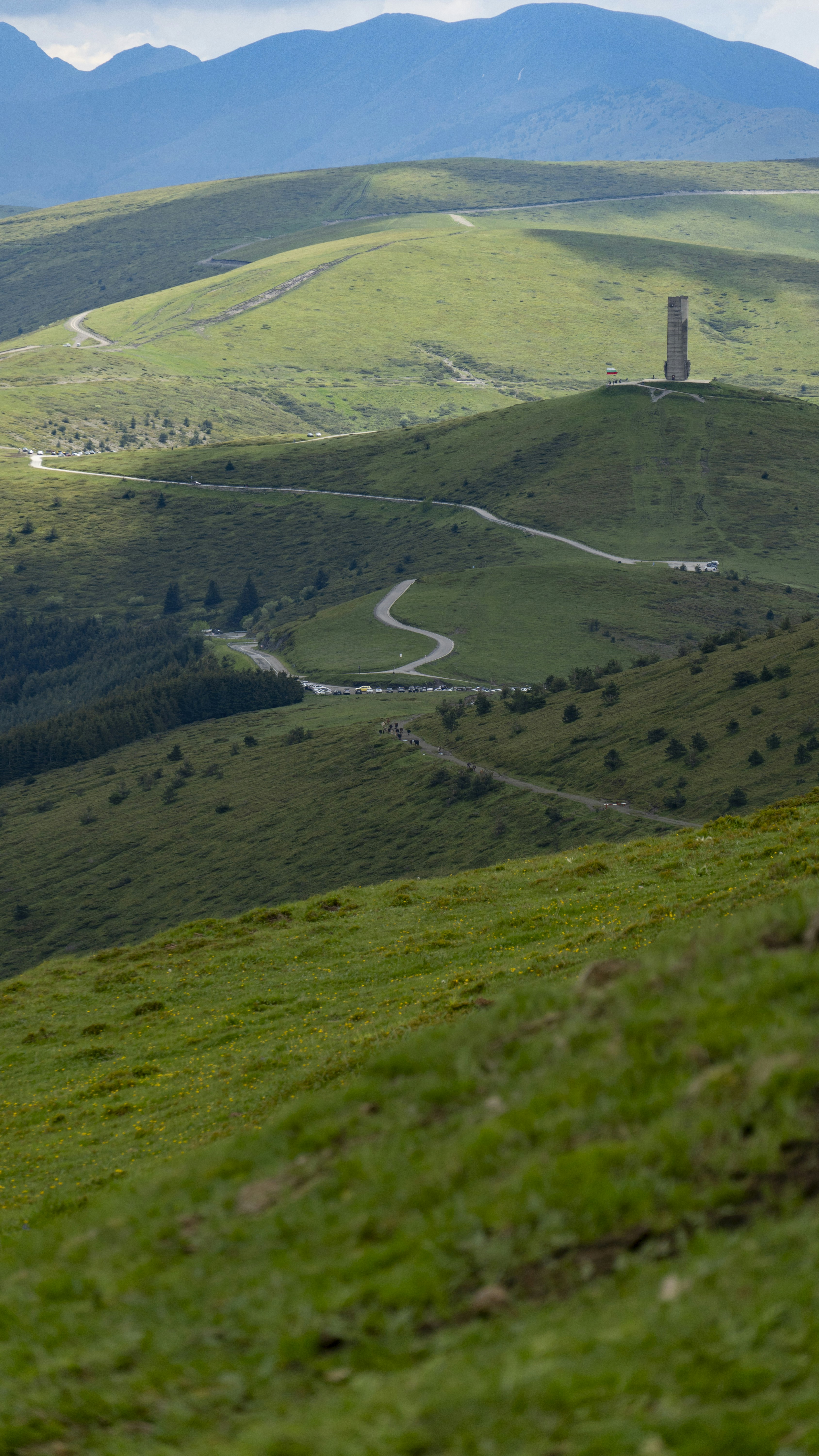 구불구불한 길은 잔디가 무성한 언덕에 있는 기념비로 이어집니다.