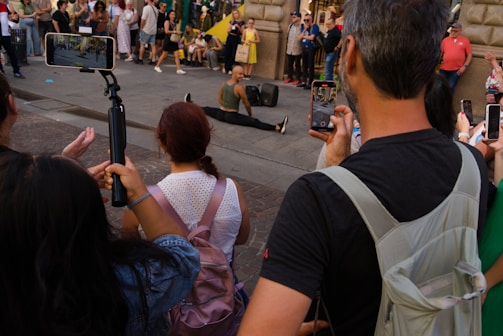 Crowd watches a performer on a street.