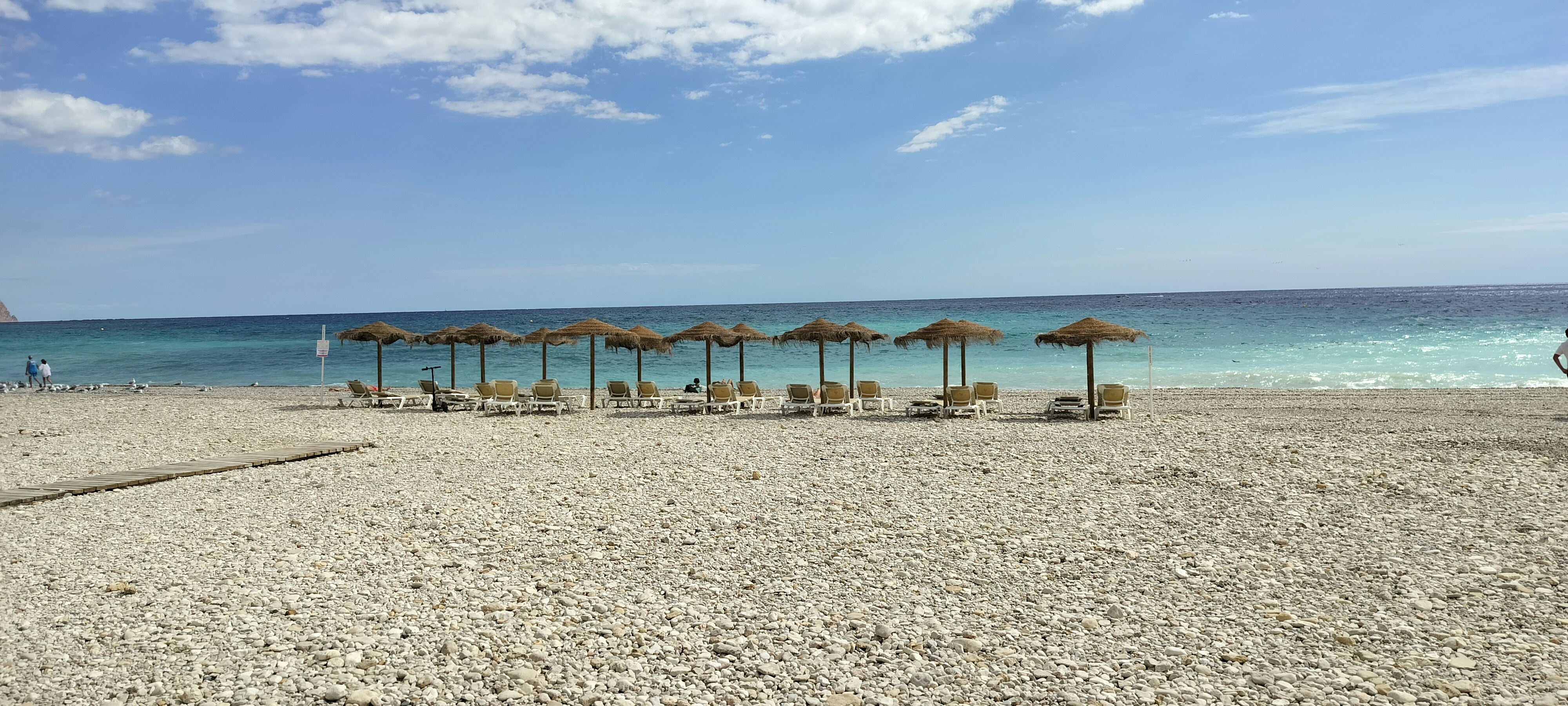 Zona de hamacas con pocas personas en playa tranquila al amanecer