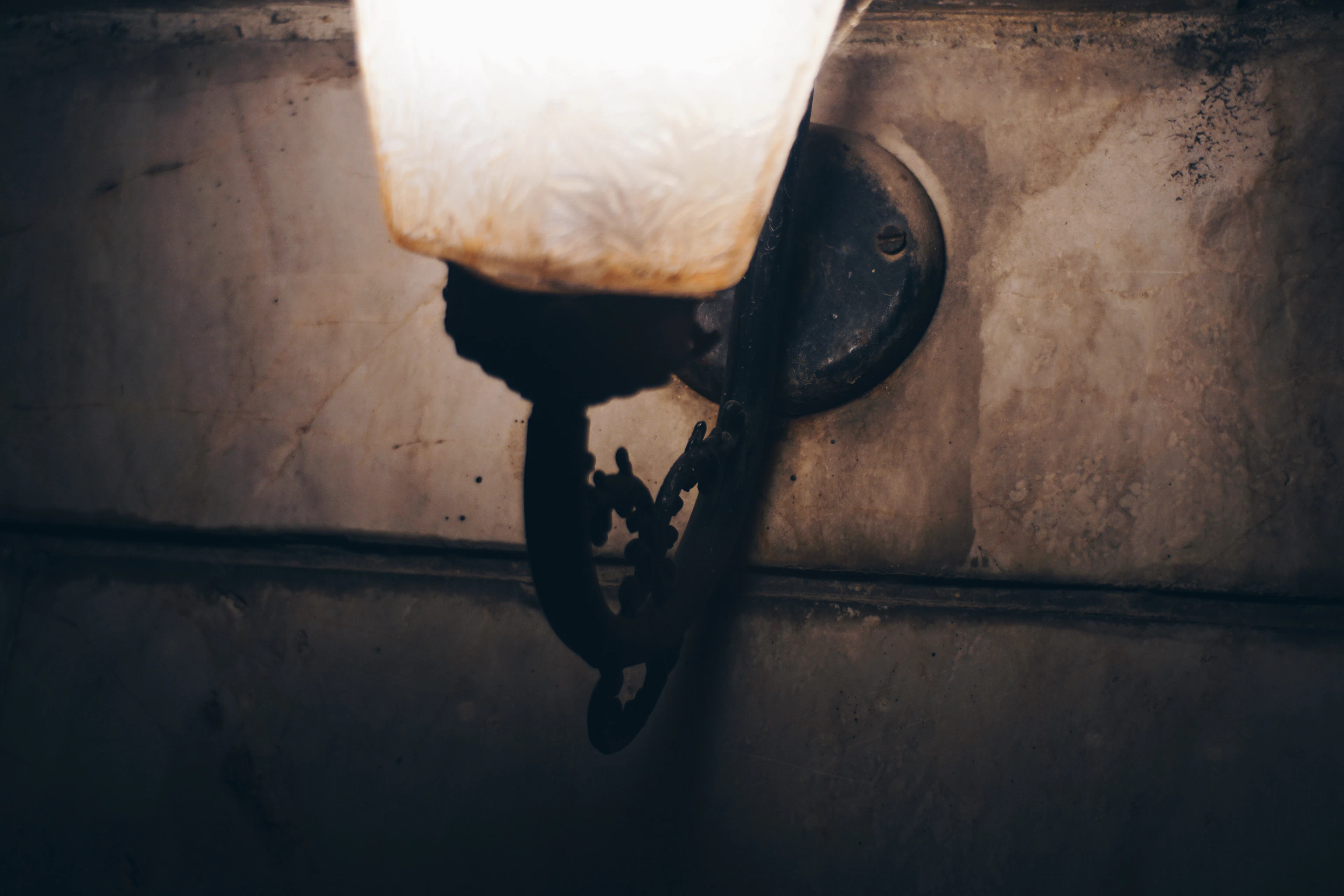 Close-up of a vintage wall sconce with a lit bulb