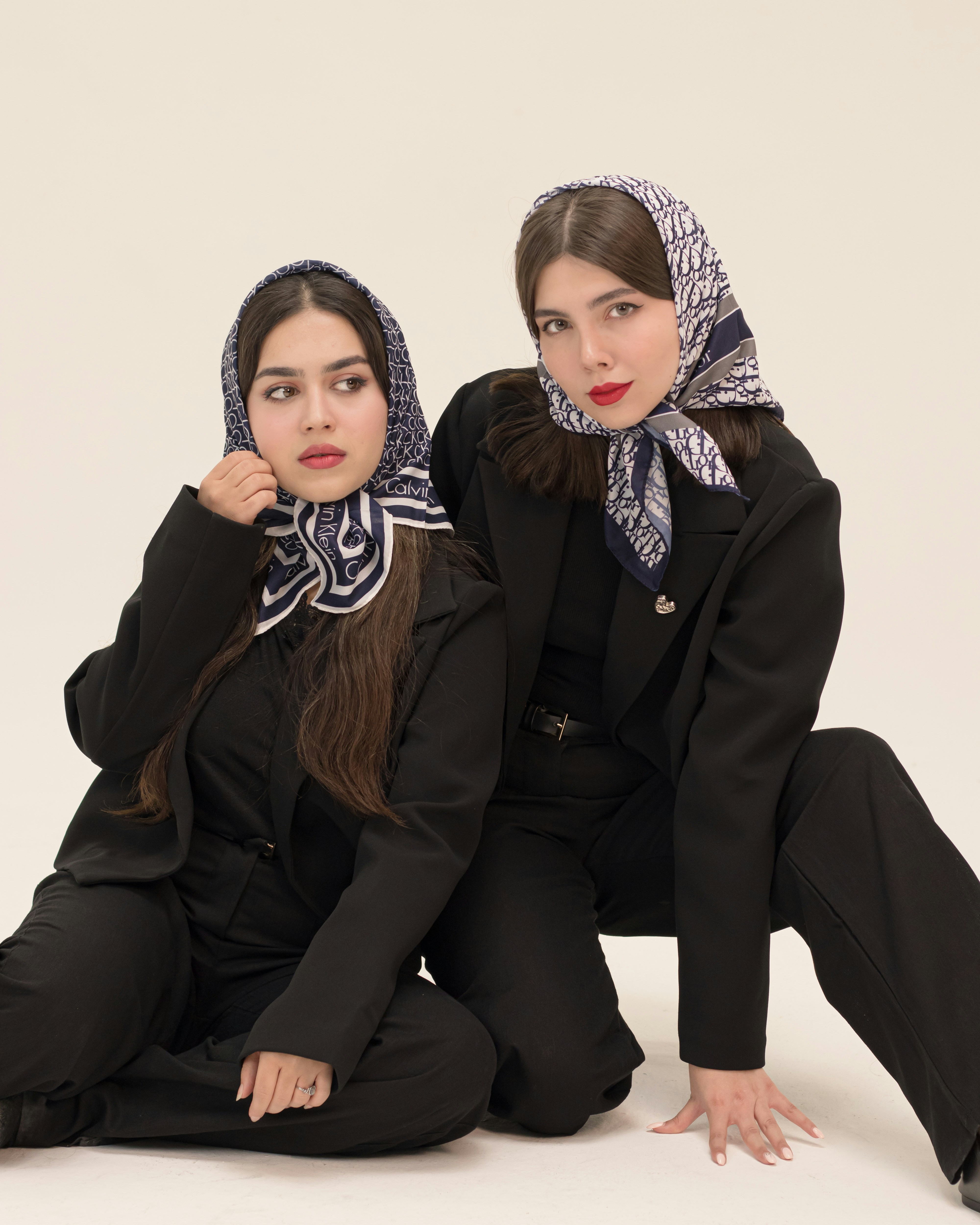 Two women in black suits and headscarves pose.