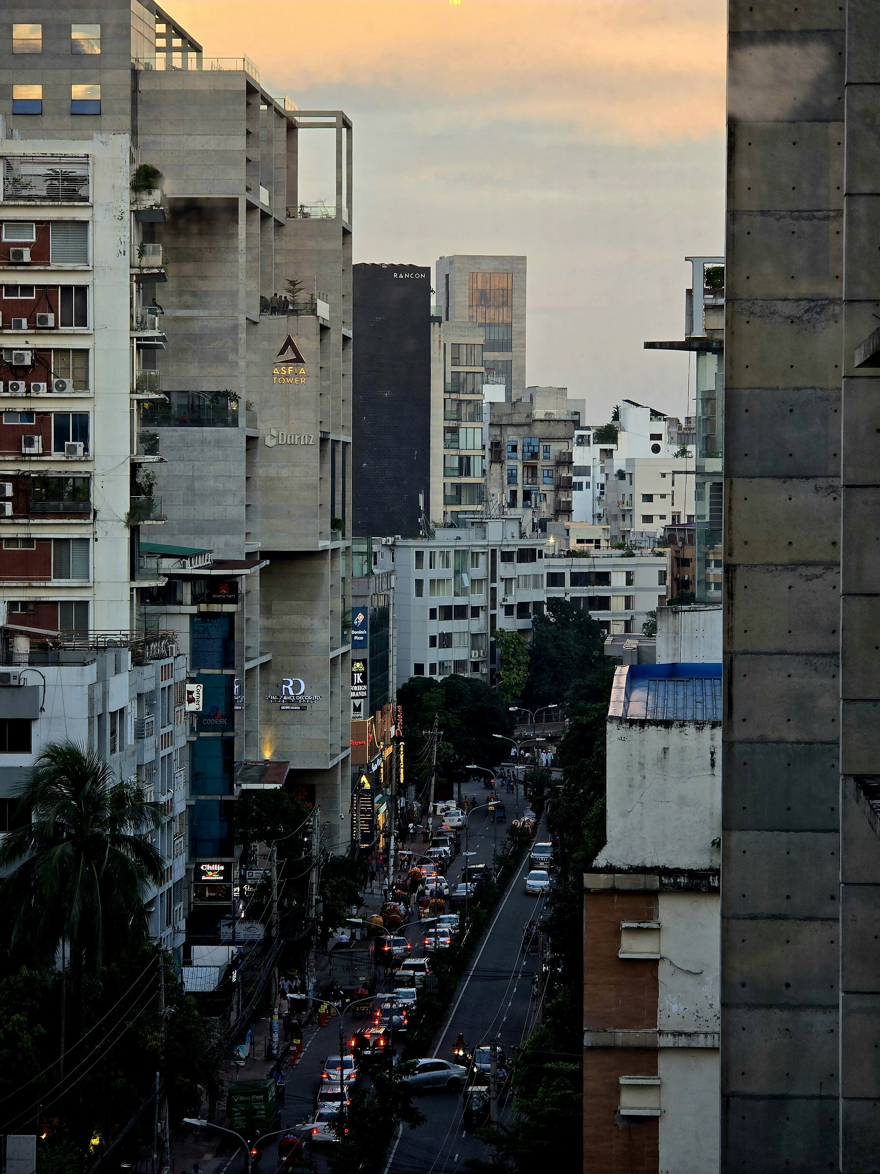 Calle concurrida con coches y edificios al atardecer