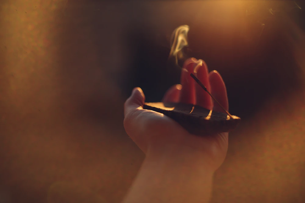 A lit oil lamp held gently in cupped hands