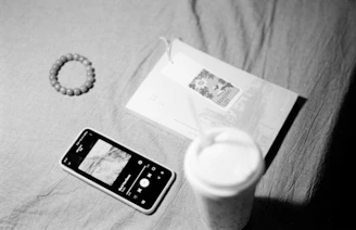 Smartphone, bracelet, and drink on a textured surface.