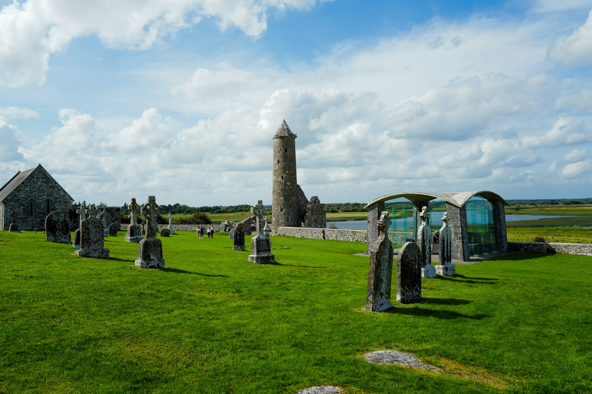 Ancient graveyard with stone ruins and round tower.