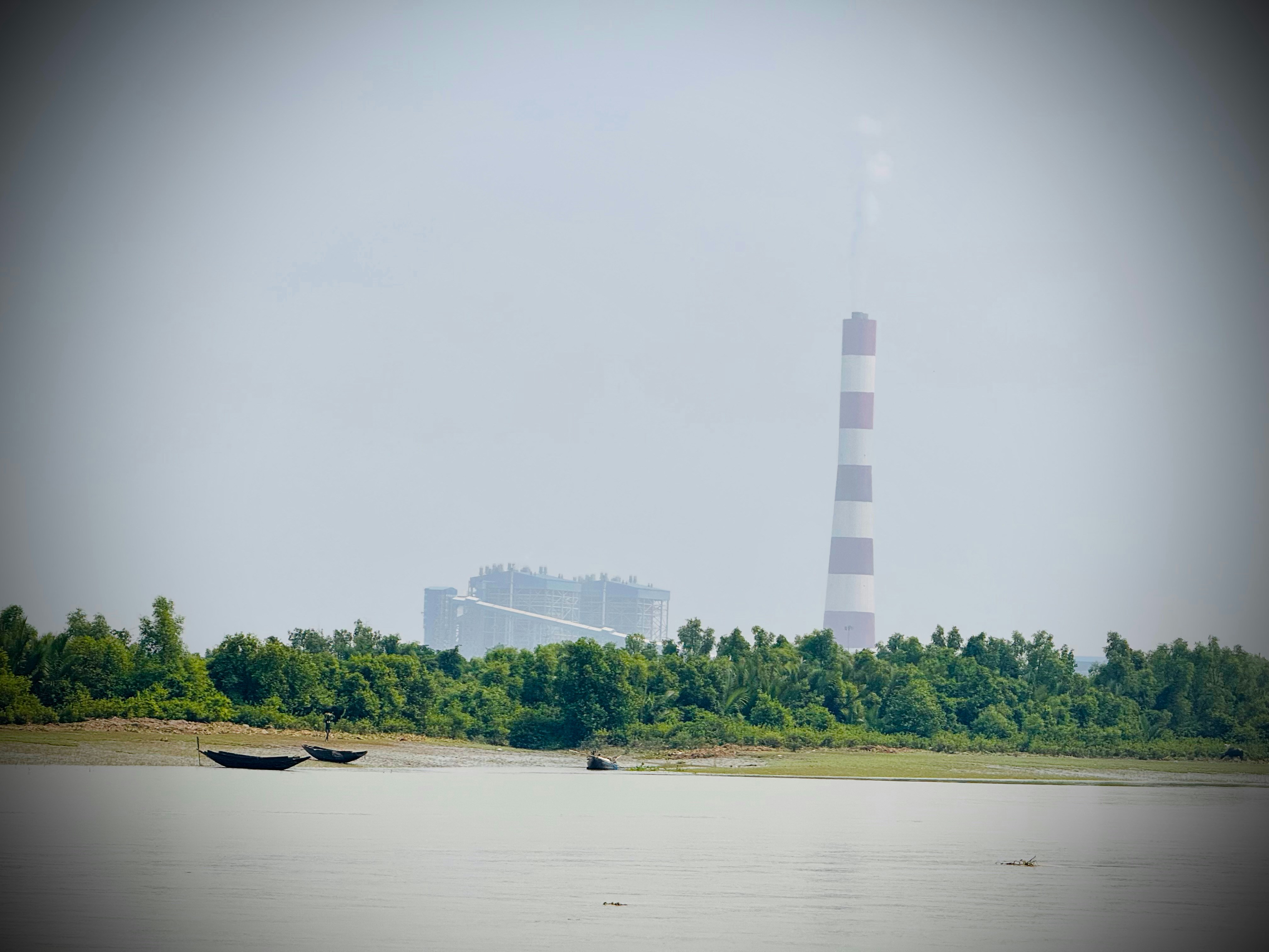 Chimenea industrial y edificios junto a un río.