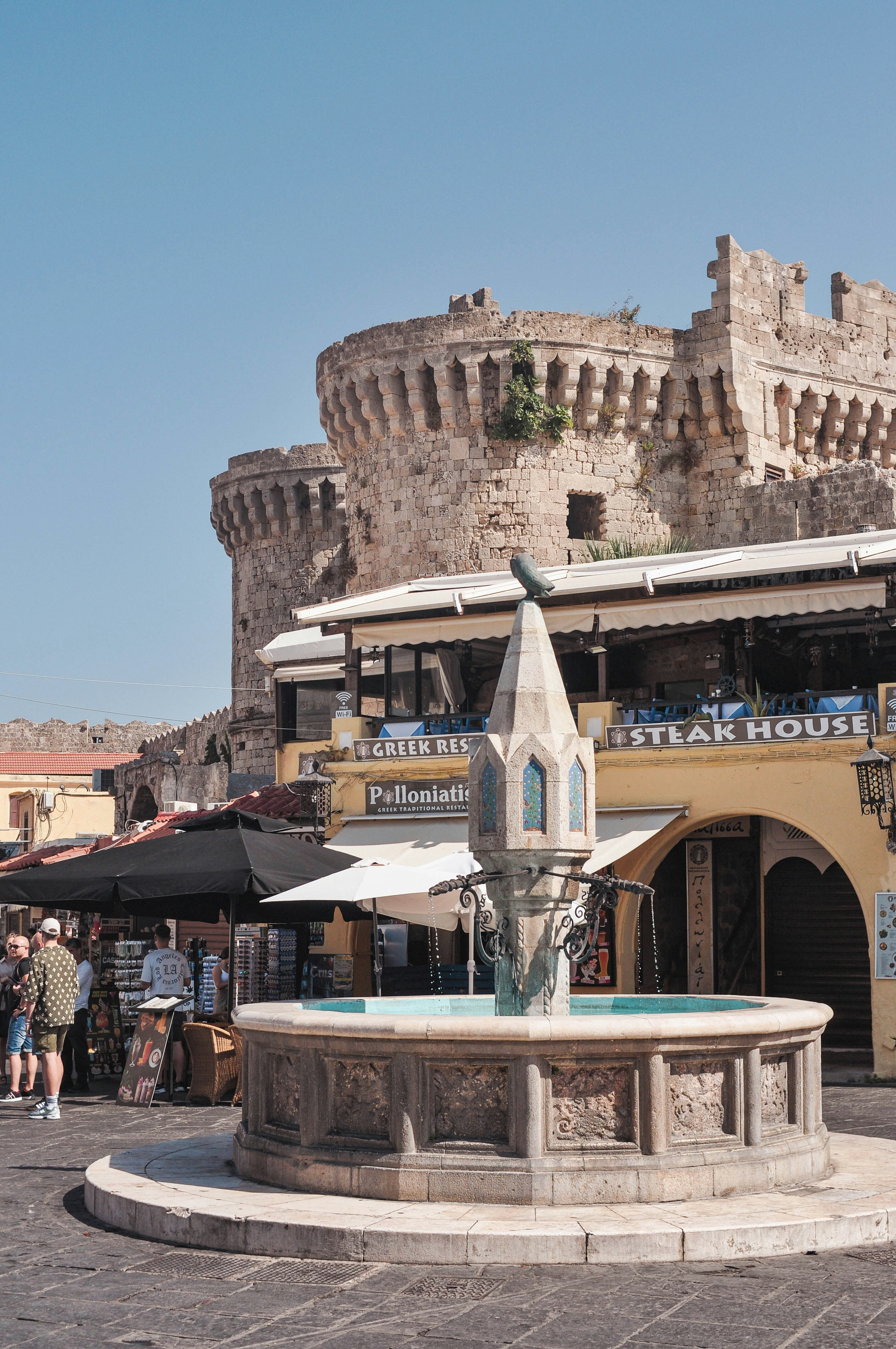 Fountain in front of medieval castle and shops.