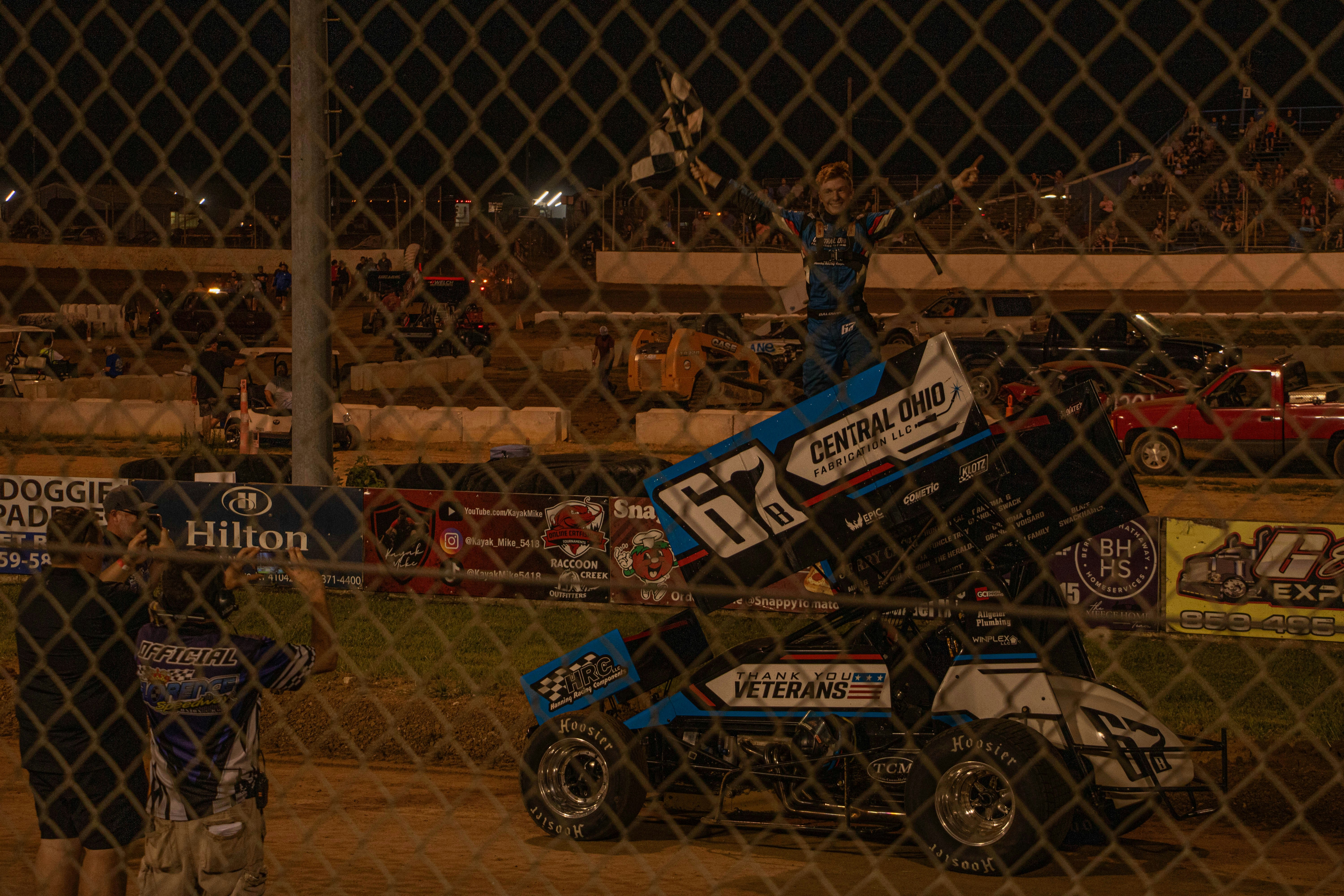 Sprint car driver celebrates victory with checkered flag