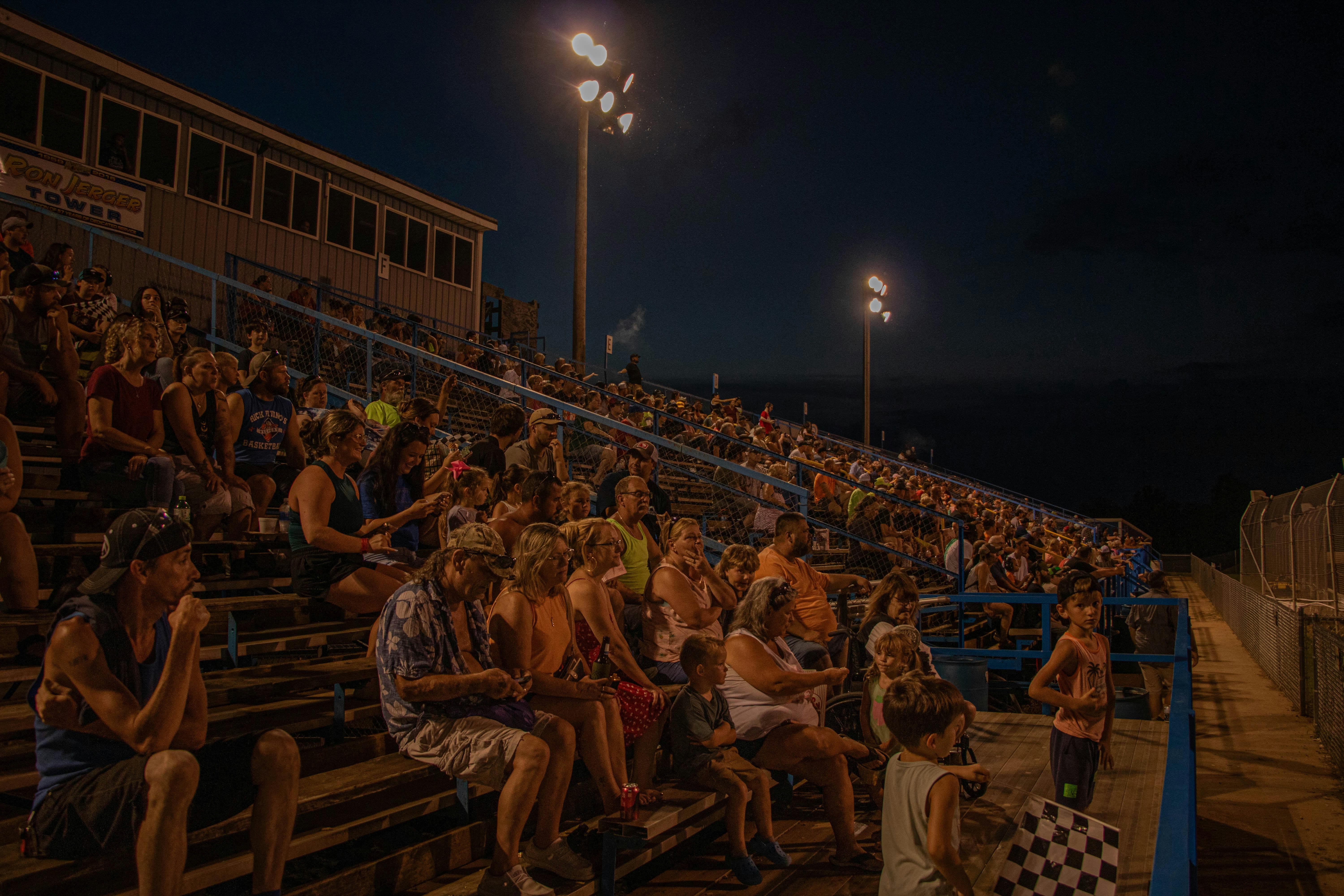 Spectators watch an event from stadium bleachers at night.