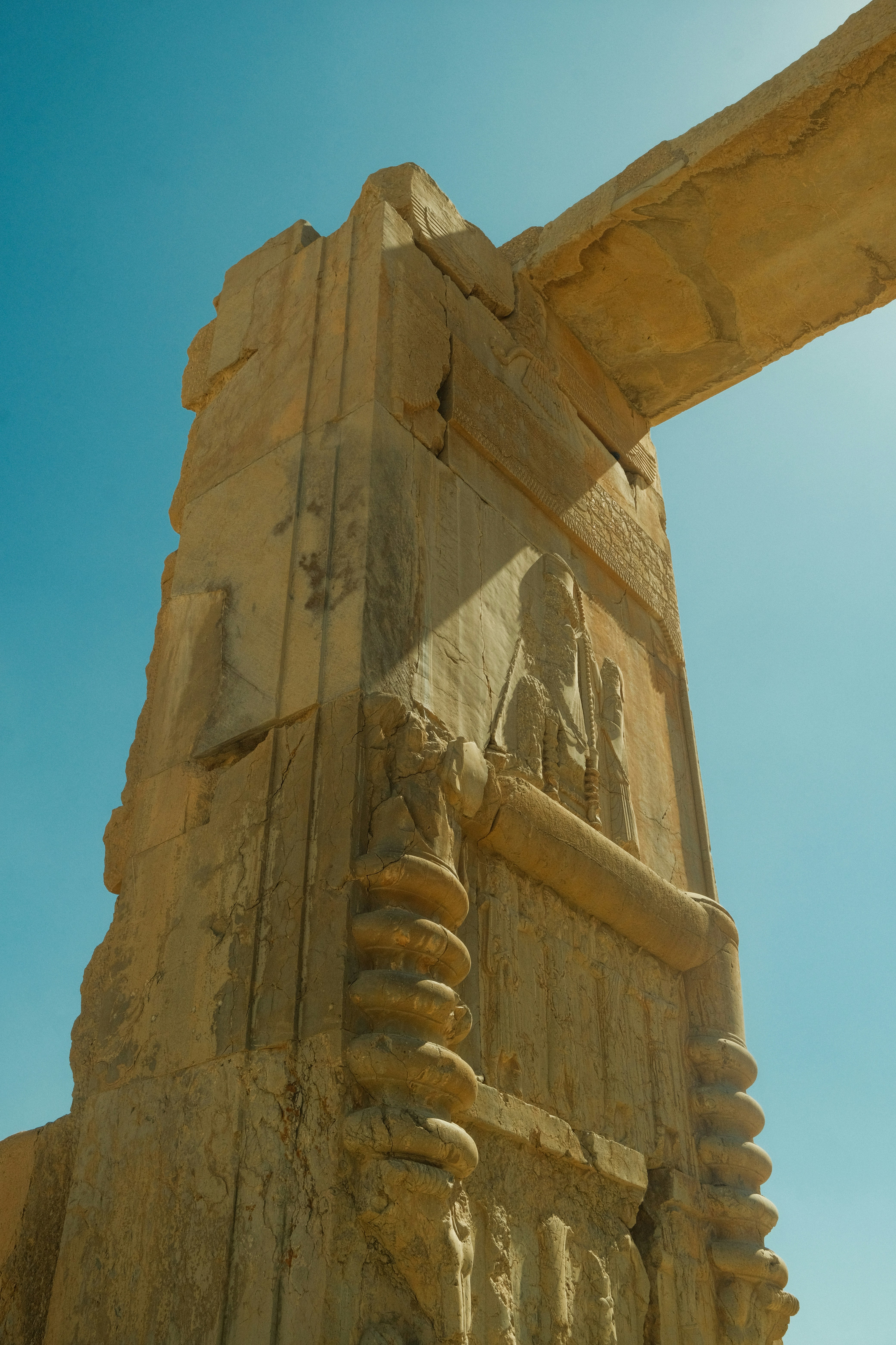 Ancient stone column with carvings against blue sky