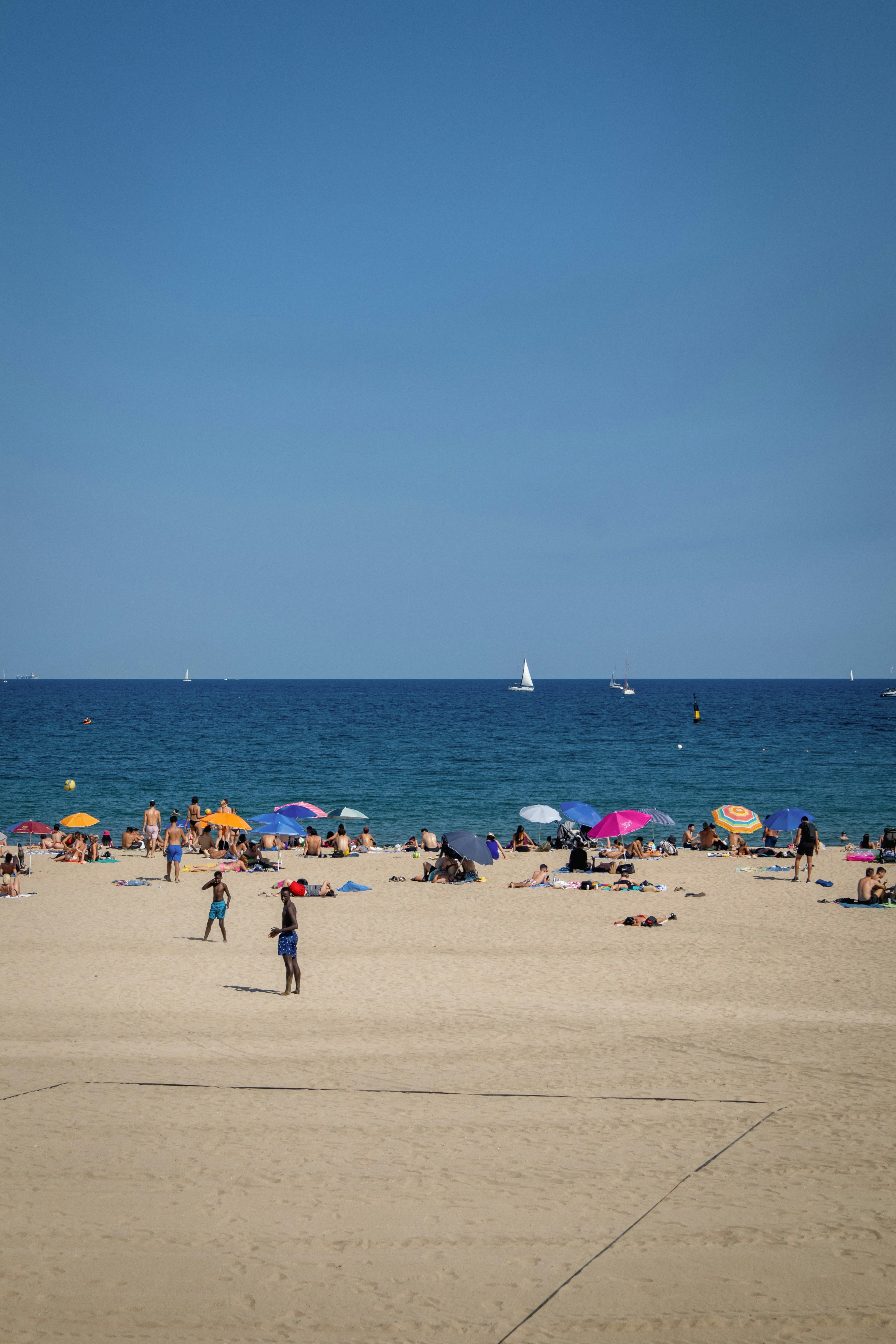 People relax on a sunny beach with blue ocean.