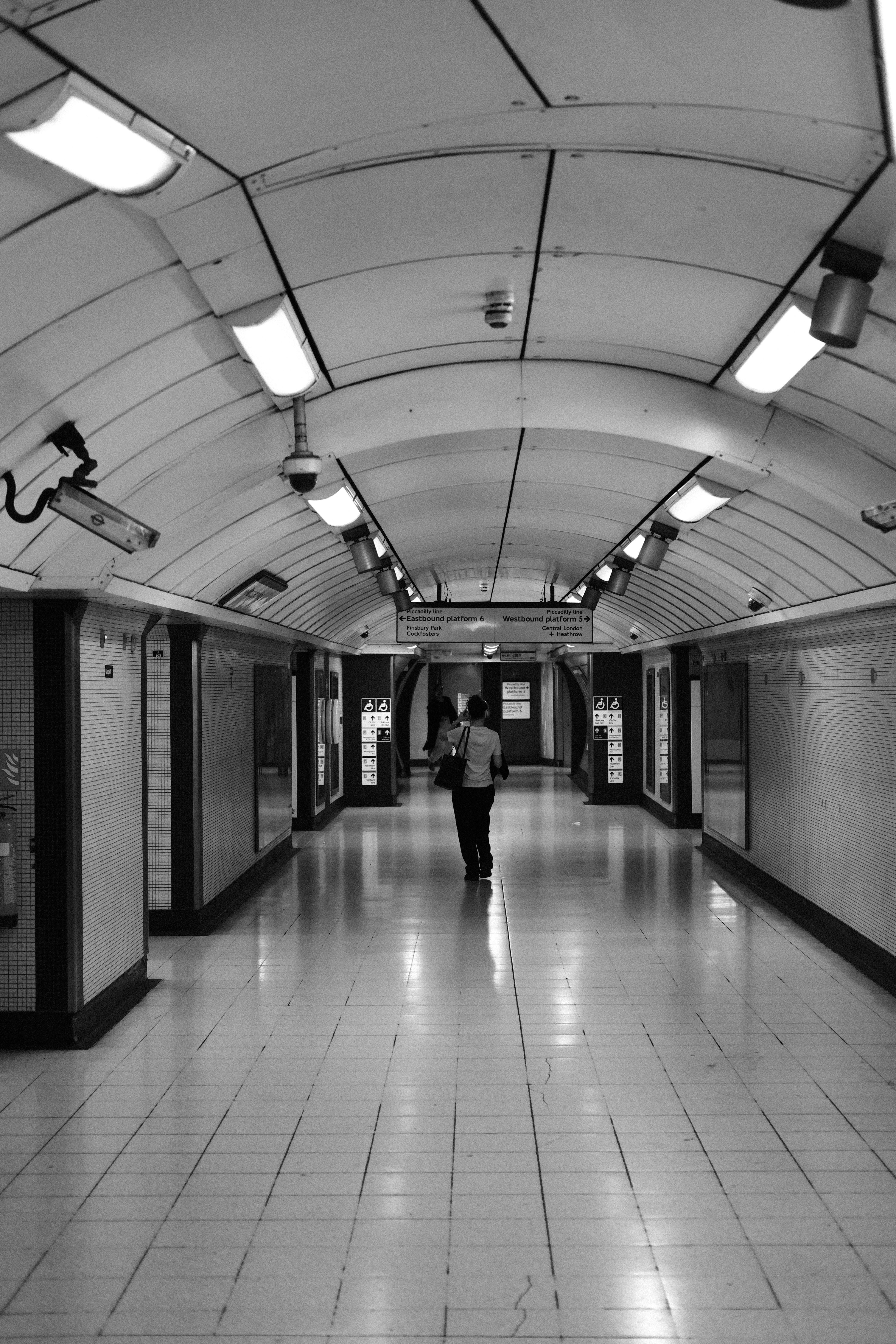 A person walks down a long, empty subway hallway.