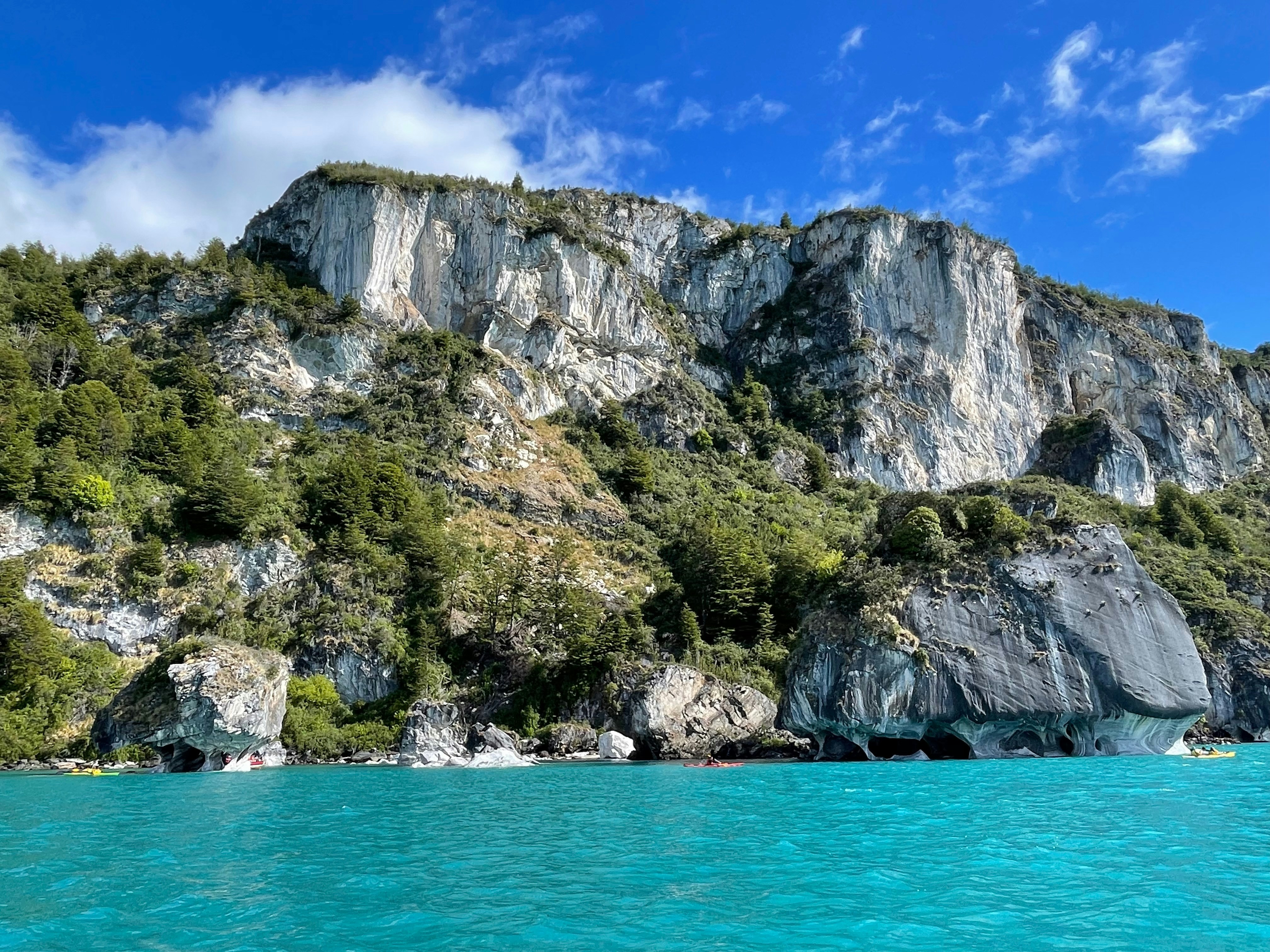 Turquoise water laps against rocky cliffs and green trees.