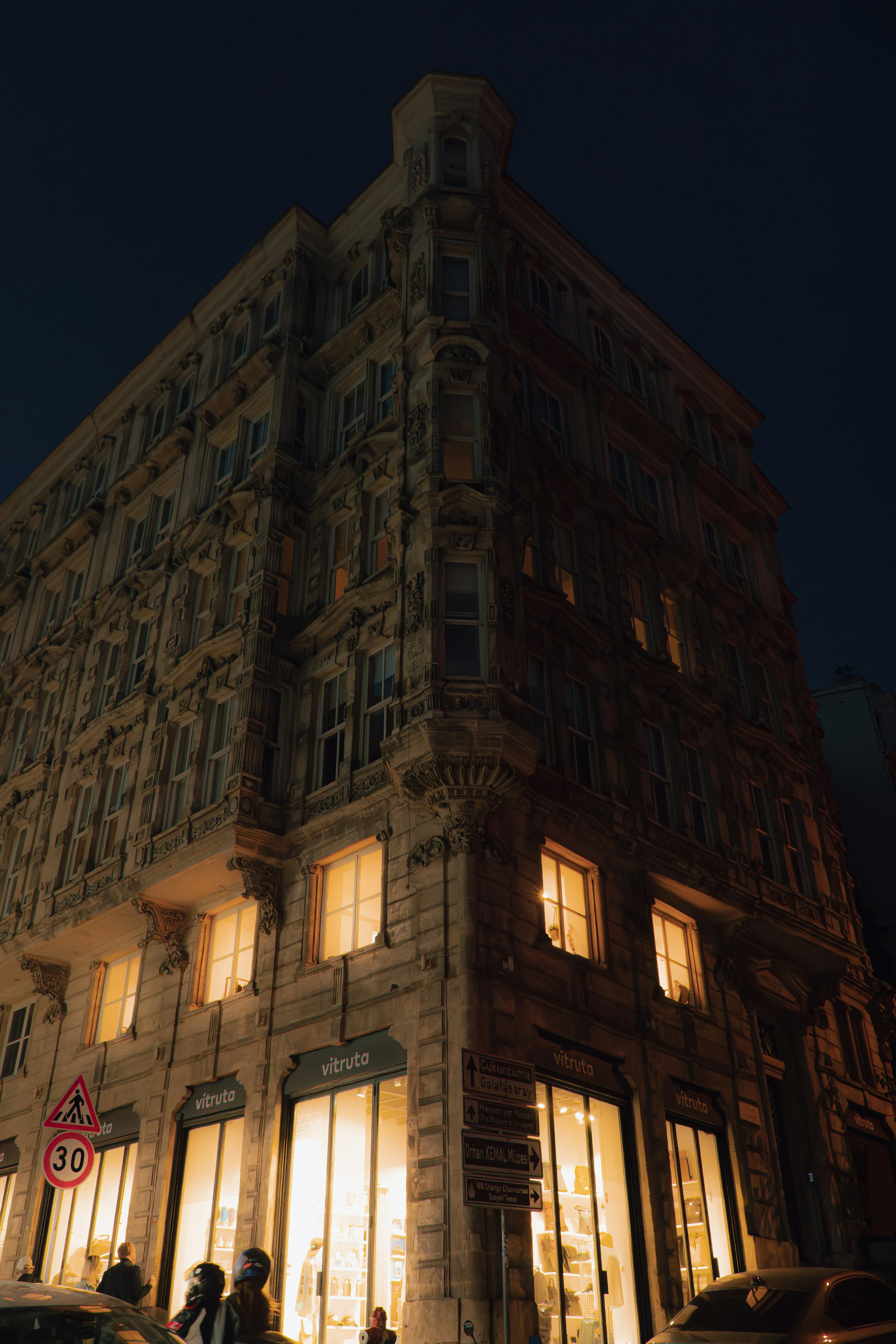 A historic stone building with illuminated storefronts at night in Istanbul