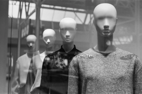 A row of faceless mannequins dressed for the season in a retail storefront window