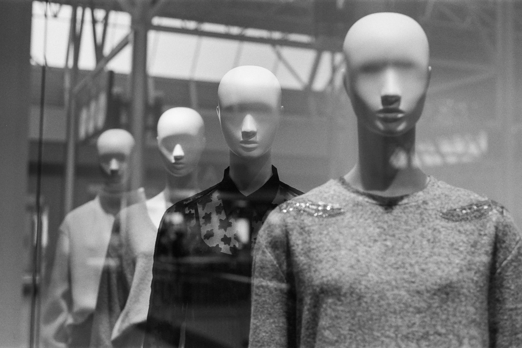 A row of faceless mannequins dressed for the season in a retail storefront window