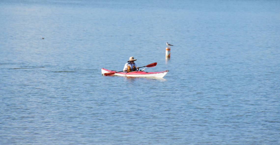 Person paddling a kayak on a calm lake