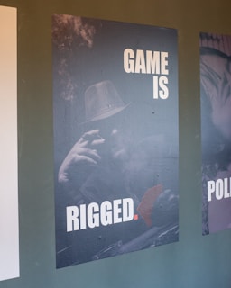 Poster with text 'game is rigged' and man.