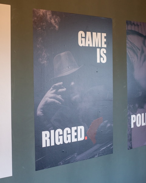 Poster with text 'game is rigged' and man.